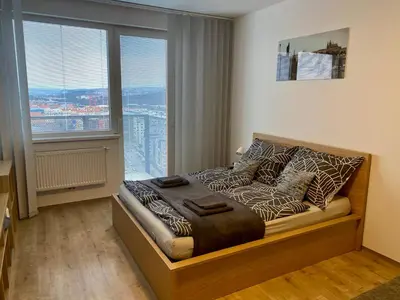 a bedroom with a bed with a large window at Apartmán ELEN, Sky View in Prague