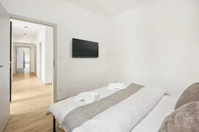 a white bedroom with a bed and a mirror at Spacious two-storey apartment with a terrace in the city center in Benešov