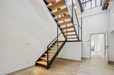 a staircase in a home with white walls and wood floors at Spacious two-storey apartment with a terrace in the city center in Benešov