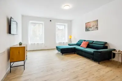 a living room with a green couch and a table at Spacious two-storey apartment with a terrace in the city center in Benešov