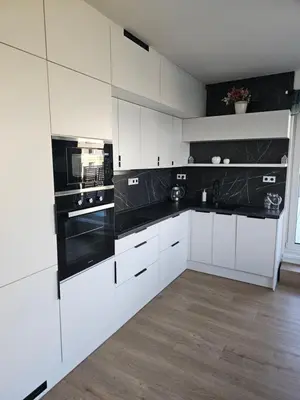 a kitchen with white cabinets and black appliances at Sun Prague - Stodůlky in Prague