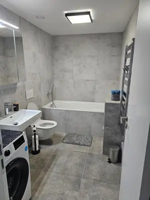 a bathroom with a tub and a sink and a washing machine at Sun Prague - Stodůlky in Prague