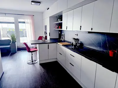 a kitchen with white cabinets and a pink chair in it at Sun Prague - Stodůlky in Prague