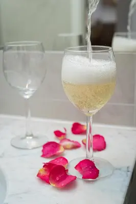 a glass of wine and two glasses of roses on a counter at Deluxe Rabbit Suite in Prague