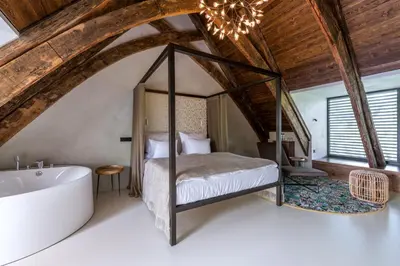 a bedroom with a bed and a tub in a attic at Yard Resort in Předboj