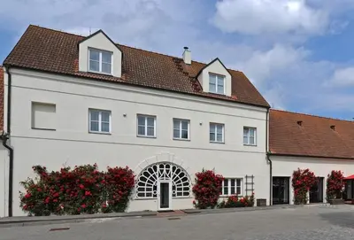 a white building with red flowers in front of it at Yard Resort in Předboj