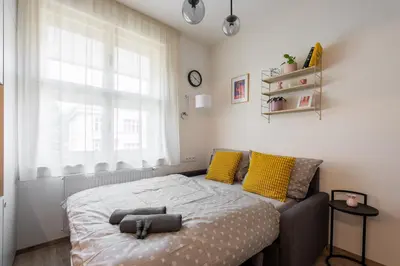 a bedroom with a bed with yellow pillows and a window at Urban Hideaway in Prague
