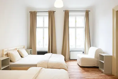 a bedroom with two beds and a couch and two windows at Masaryk Lounge in Prague