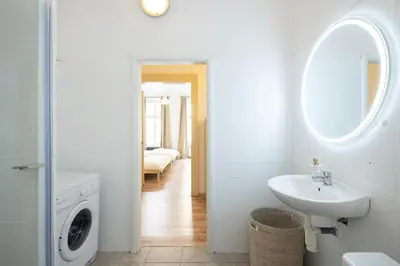 a white bathroom with a sink and a washing machine at Masaryk Lounge in Prague