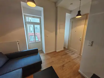 a living room with a blue couch and a window at Modern 1BR in trendy Žižkov in Prague