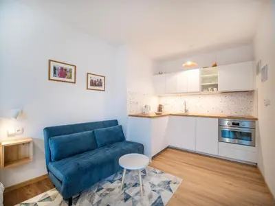 a living room with a blue couch and a kitchen at Apartmán Ve středu dění in Poděbrady