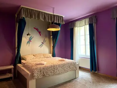a bedroom with a bed with purple walls and birds on the wall at The Dragonfly Residence in Prague
