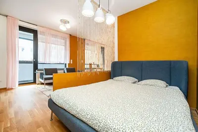 a bedroom with a blue bed and a yellow wall at Spacious studio with free parking in Prague