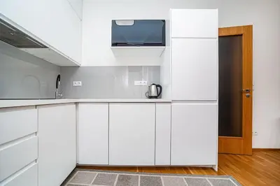 a kitchen with white cabinets and a tv on the wall at Spacious studio with free parking in Prague