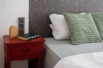a bed with a red night stand with a book on it at Zen Garden in Prague