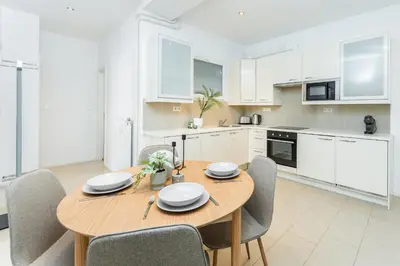 a kitchen and dining room with a wooden table and chairs at Rentero Central Two Bedroom Apartment in Prague - Two bathroom - Parking in Prague