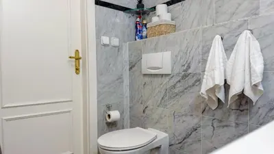 a bathroom with a white toilet and marble tiles at Cozy Apartment in central Prague near Wenceslas Sq in Prague