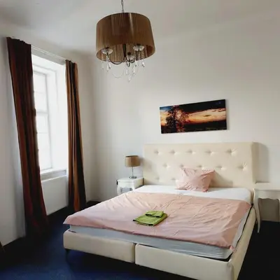 a bedroom with a bed with pink sheets and a chandelier at Just 3 min Walk Old Town Center private room E in Prague
