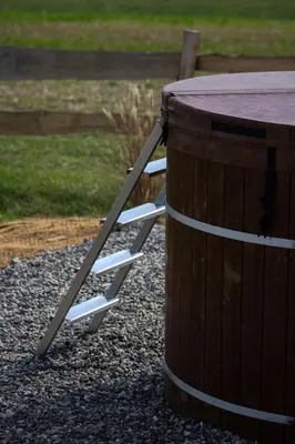 a wooden table with white chairs next to a wooden barrel at Tiny u koníků