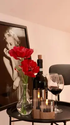 a table with a bottle of wine and red flowers at Entire 2nd floor of Villa with 3bedroom with large garden,BBQ,pool,sauna,free parking in Popovičky
