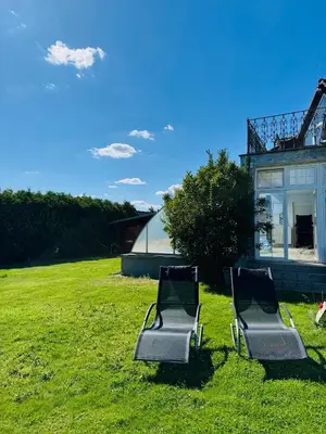 two chairs sitting in the grass in front of a house at Entire 2nd floor of Villa with 3bedroom with large garden,BBQ,pool,sauna,free parking in Popovičky