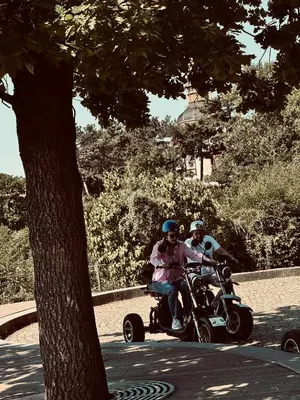 two people riding on a four wheeler on the street at Kamenicka new! in Prague