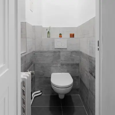 a white toilet in a bathroom with gray tiles at Authentically stylish apartment with a mystical view GOLEM in Prague