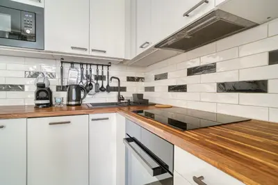 a kitchen with white cabinets and a wooden counter top at Fügner's apartment by Rentez in Prague