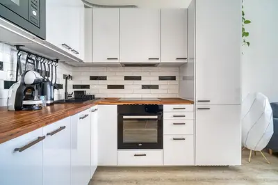 a kitchen with white cabinets and a wooden counter top at Fügner's apartment by Rentez in Prague