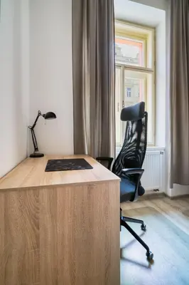 a desk with a black chair and a lamp at Fügner's apartment by Rentez in Prague