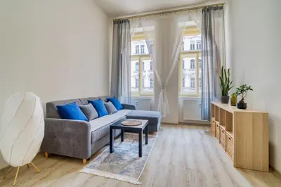 a living room with a gray couch and blue pillows at Fügner's apartment by Rentez in Prague