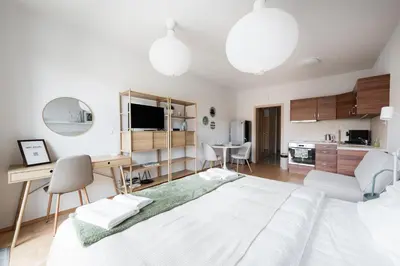 a bedroom with a large white bed and a kitchen at Stylish and Comfortable Studio in Prague