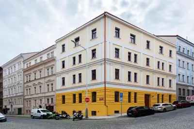 a yellow and white building with cars parked in front of it at Good Mood in the Zizkov Hood Prague in Prague