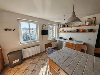 a kitchen with a table and two windows at Elegant and Spacious 4BR Loft in Charming Vinohrady in Prague