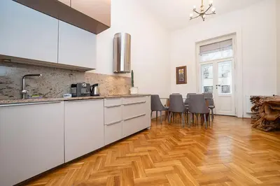 a kitchen with white cabinets and a wooden floor at Museum Quarter Elegance Suite in Prague