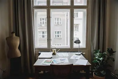 a table in front of a large window with a desk sidx sidx sidx at Stylish and unique 2 bedroom flat with balcony in Letna in Prague