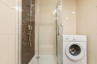 a bathroom with a shower and a washing machine at Welcometothejungleapartment in Prague