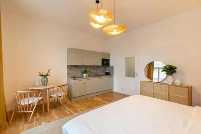 a bedroom with a bed and a table and a kitchen at Welcometothejungleapartment in Prague