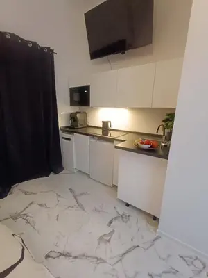 a kitchen with white cabinets and a marble floor at Apartmány Podol in Prague