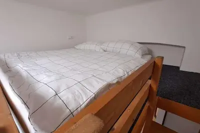 a bed with white sheets on a wooden frame at Cozy studio in Prague favorite neighborhood in Prague