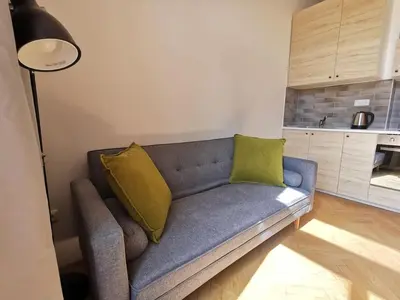 a living room with a blue couch with two yellow pillows at Modern studio with excellent transport links in Prague
