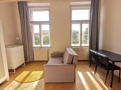 a living room with a chair and a table and windows at New petite studio in bohemian suburb in Prague