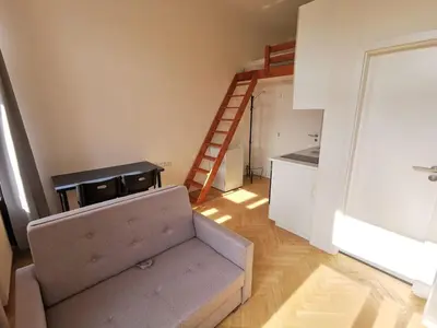 a living room with a couch and a kitchen at New petite studio in bohemian suburb in Prague