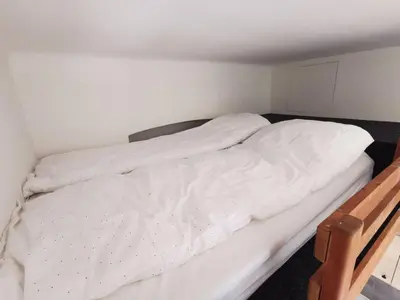 a bedroom with a white bed with a wooden frame at New petite studio in bohemian suburb in Prague