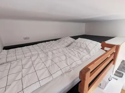 a bedroom with a white bed with a wooden frame at Cosy and simple well located studio in Prague