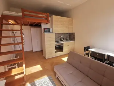 a living room with a couch and a kitchen at Cosy and simple well located studio in Prague