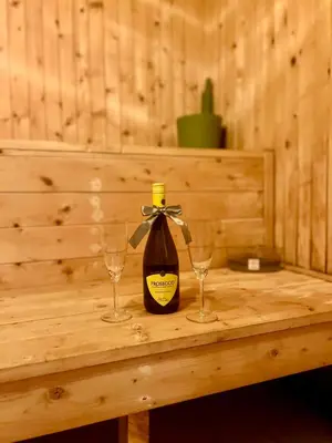 a bottle of wine and two glasses on a wooden table at Chata Roda s vnitřní saunou in Rabyně