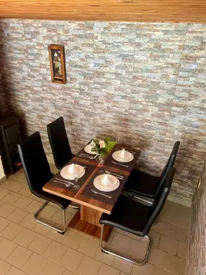 a dining room table with black chairs and a brick wall at Chata Roda s vnitřní saunou in Rabyně