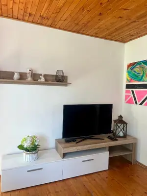 a living room with a tv on a white wall at Chata Roda s vnitřní saunou in Rabyně