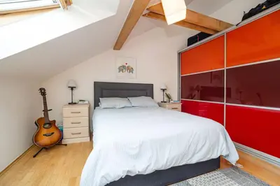 a bedroom with a large bed and a guitar at Bright and airy apartment in unique suburb in Prague